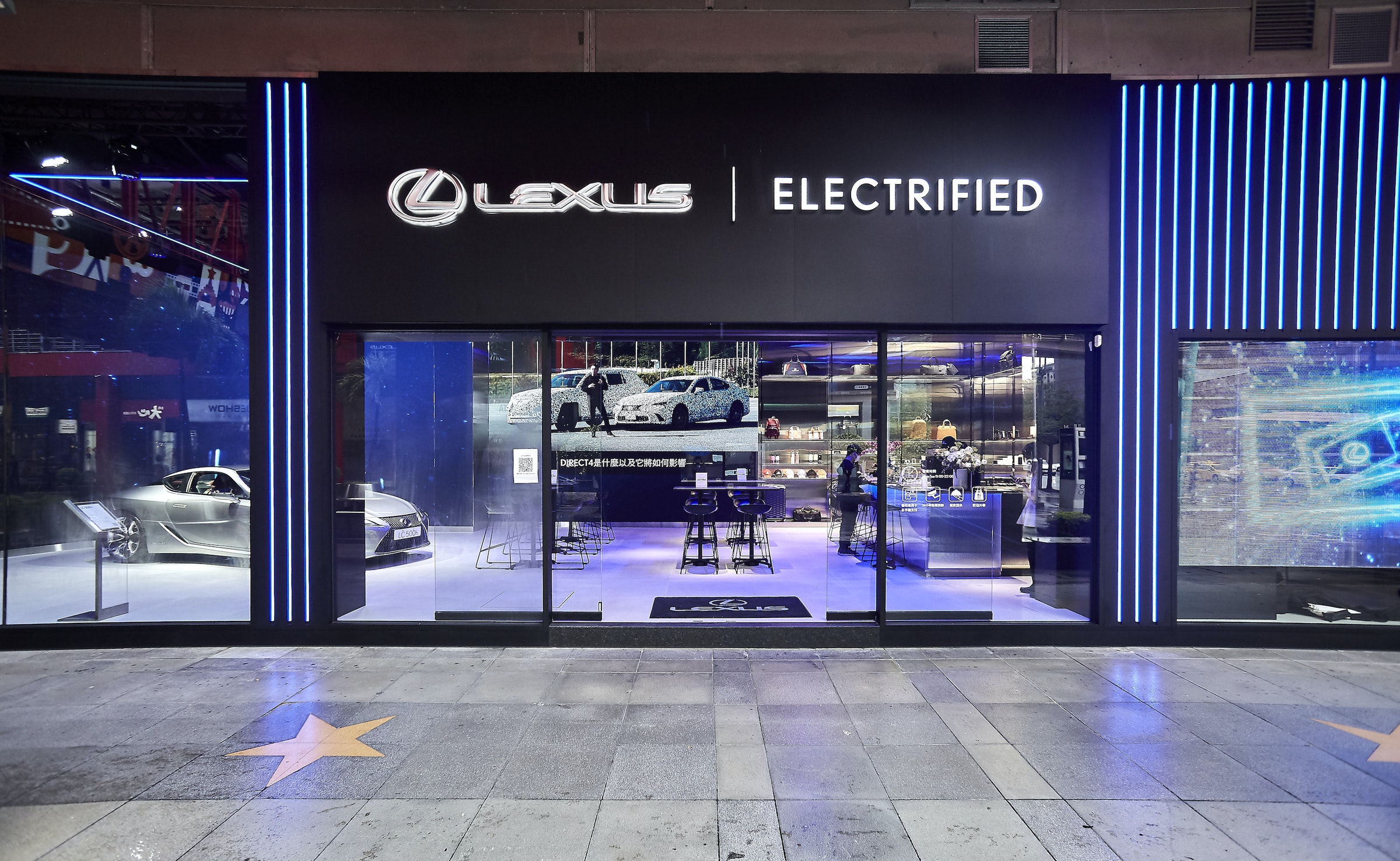 照片中提到了QLEXUS| ELECTRIFIED、EXTE、WOHEB，跟雷克薩斯有關，包含了顯示裝置、顯示裝置、數碼展示廣告、展示窗、汽車代理商