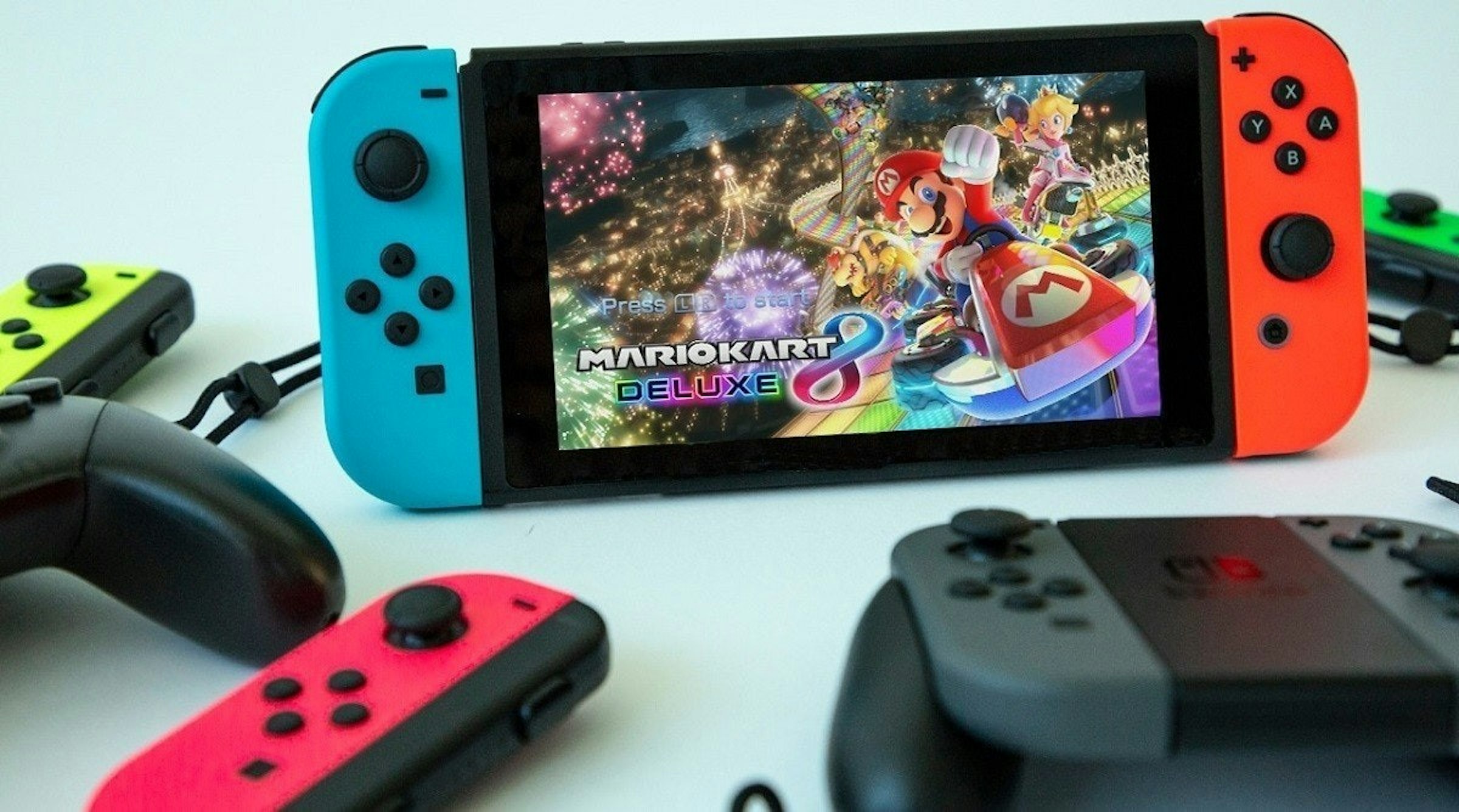 照片中提到了Press R、MARIOKART、DELUXE，跟馬里奧賽車有關，包含了遊戲控制器、的PlayStation 4、Xbox One、超級任天堂娛樂系統、任天堂開關精簡版
