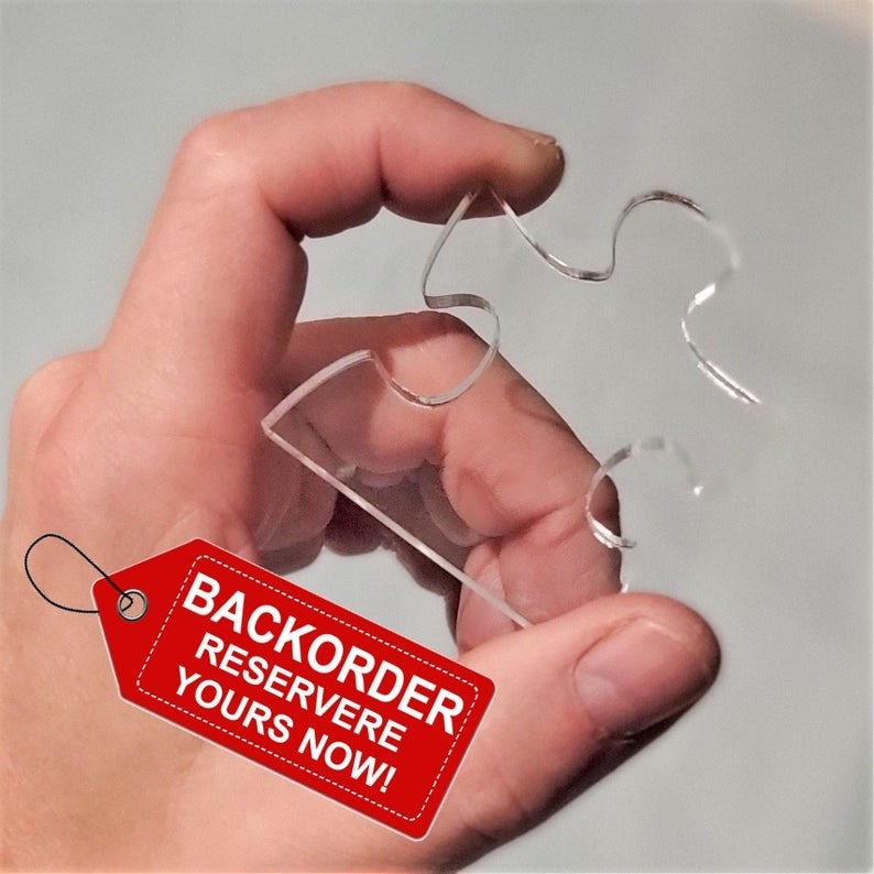 照片中提到了BACKORDER、RESERVERE、YOURS NOW!,包含了拼圖遊戲、拼圖遊戲、難題、不可能的難題看不見的,不可能難題的透明亞克力拼圖、紐約拼圖公司