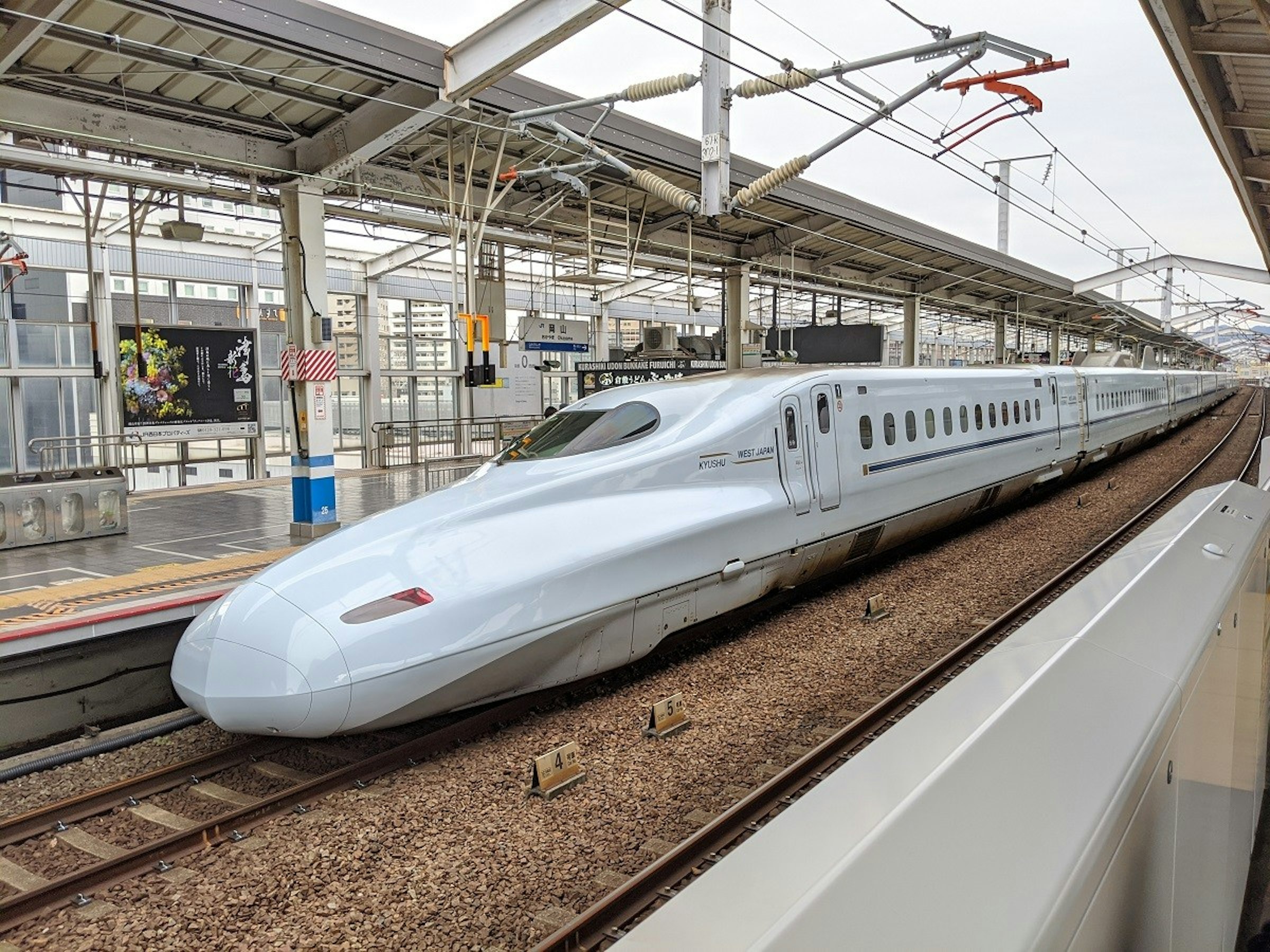 照片中提到了KIRASHINI UDON BUNKAKE FURUICHI RI、WEST JAPAN、KYUSHU，包含了高速火車、高速火車、公共交通、鐵路交通、培養
